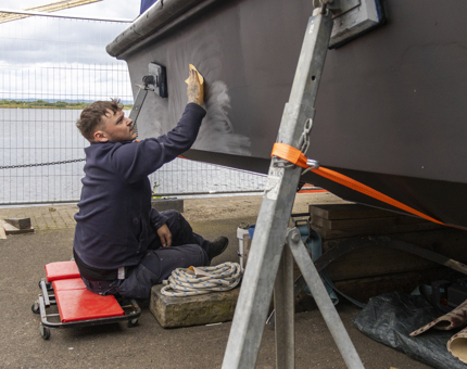 The Maintenance man is sanding the hull of the Fast Motor Launch.