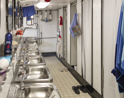 A communal bathroom containing shower cubicles and wash basins. 