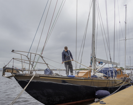A man from the Maintenance team is hosing down the racing yacht, Bloodhound.  