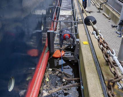 A man is on a platform collecting debris from out of the water. 