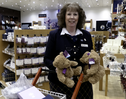 A woman in the Gift Shop is re-stocking teddy bears.