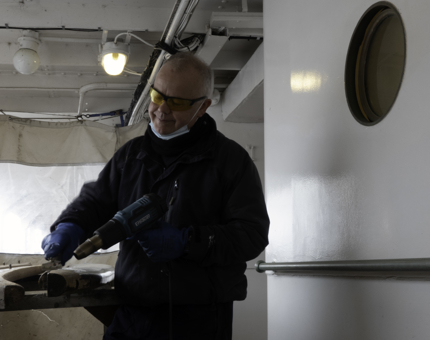 A man is removing varnish from a handrail. 