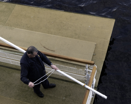 A man from Maintenance is preparing a flag staff holder on the pontoon. 