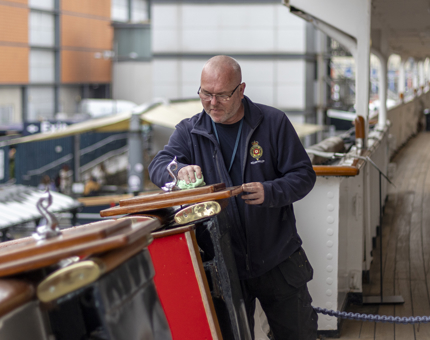 A man from Facilities is polishing the top of the Royal Brow. 
