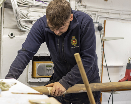 A man sanding a handrail from Britannia. 