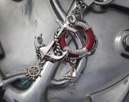 A silver-coloured keyring with nautical charms of an anchor, perry buoy, ship's wheel and sailing boat. 