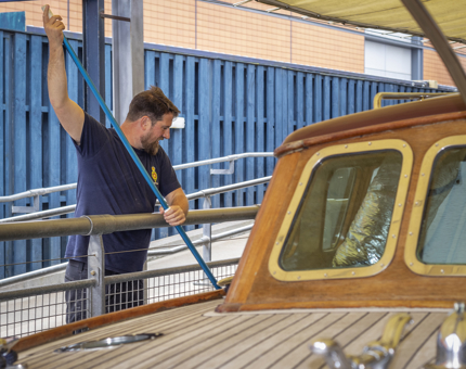 A member of the Maintenance team is using a long pole to clean the Royal Barge pond. 