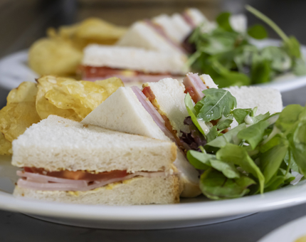 Triangles of ham sandwich with salad and crisps.