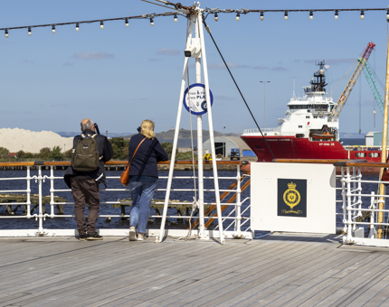 Two visitors listen to audio guides on the Verandah Deck.