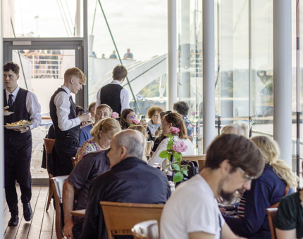 A busy day in the Royal Deck Tearoom where many visitors are sitting at tables enjoying refreshments.