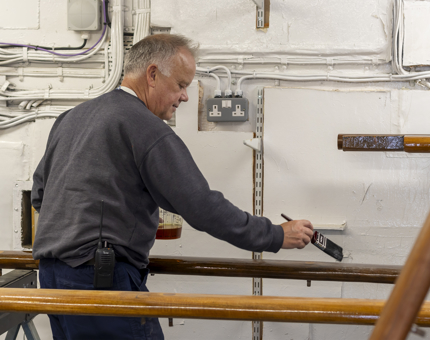 A member of the Maintenance team varnishing a handrail.