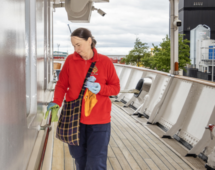A Housekeeper polishing a handrail. 