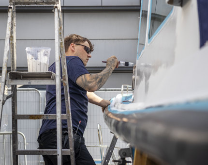 A man is painting the Activity Boat. 