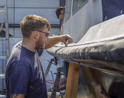 A man from the Maintenance team is sanding the Fast Motor Launch. 