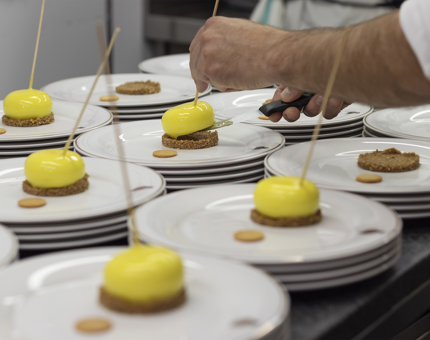 A close up of a hand placing lemon cheesecakes on to plates. 