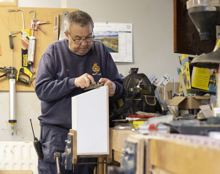 A man in a workshop making a box. 