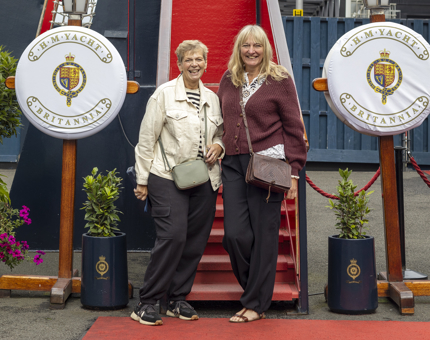 Two women posing for a photo in front of the stairs to the Royal Brow, a walkway onto the ship.