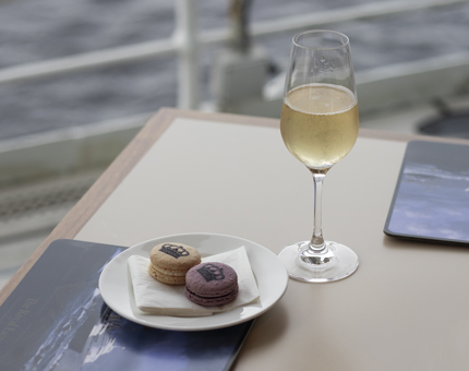 A table with a glass of Champagne and a plate with two macarons on it. 