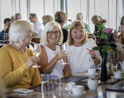 Four ladies sitting at a table holding glasses of Champagne.