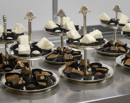 Six cake stands with brown and white cakes on it.