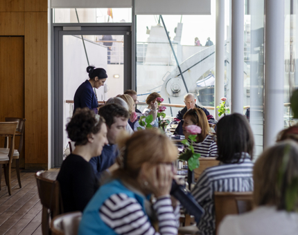 Visitors sitting at tables by the window in the Royal Deck Tearoom. 