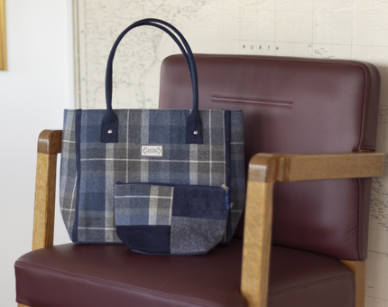 A blue tartan bag sitting on a brown chair.