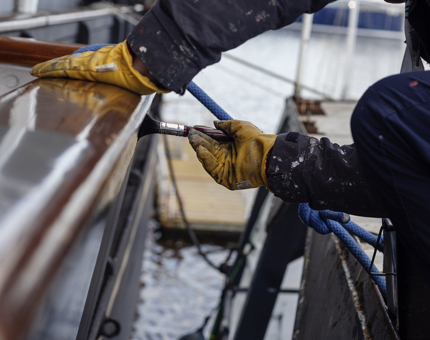 Close-up of hands painting the side of the ship. 