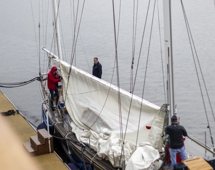 Three men hoisting a sail on a yacht. 