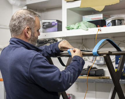 A man taping up a luggage stand for varnishing. 