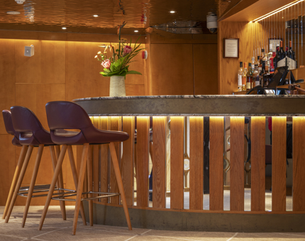 The bar area in Fingal's Ballroom, featuring three purple bar stools and and a vase of flowers. 