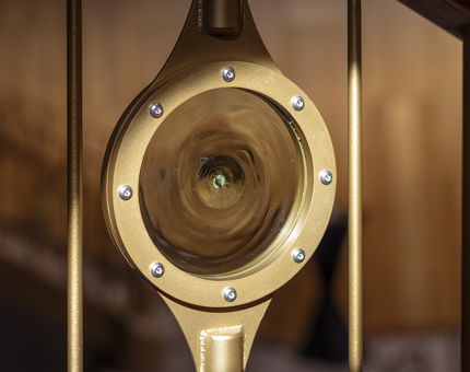 A round glass detail from the railing on a staircase.