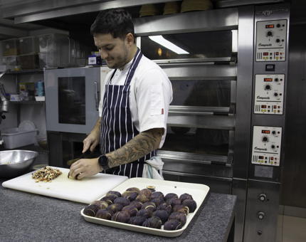 Chef slices ingredients preparing them for a dish. 