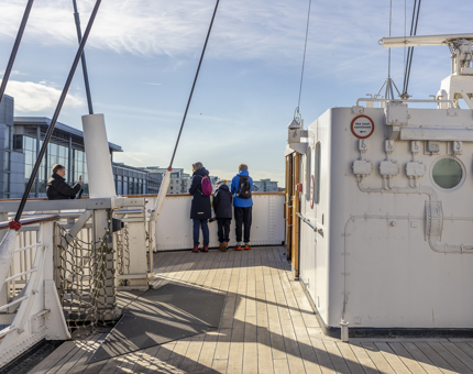 A family of three people look over the side of the Bridge. 