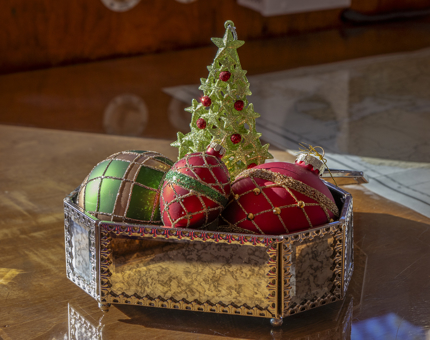 Three Christmas baubles and a tree decoration in a silver display box.
