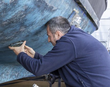 A man removing the sea water intake valve on the Fast Motor Launch boat. 