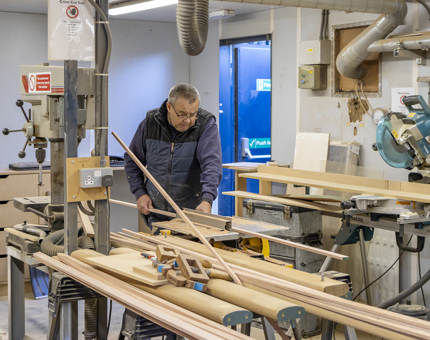 A man cutting wooden beading. 