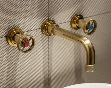 A close-up of a brass tap and handles.