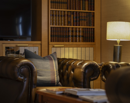 A brown leather chair and a lamp sitting in front of a bookshelf.