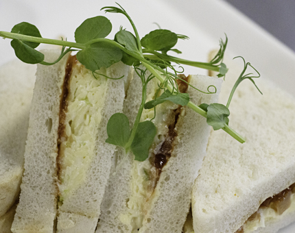 Close-up of cheese and chutney sandwiches on white bread with a salad garnish. 