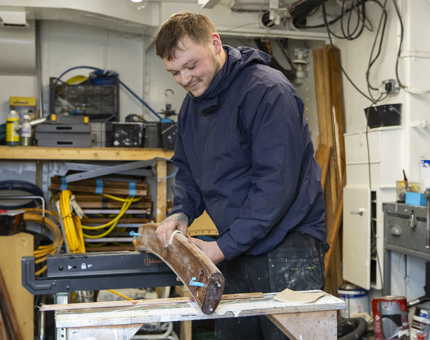 A man sanding a handrail in the workshop.