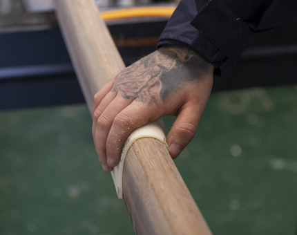 A closer look at a hand sanding a handrail.