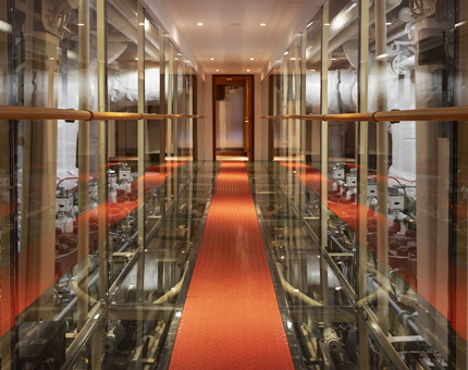 A walkway with views into an engine room. 