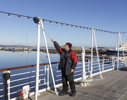 A member of the Facilities team dusting the lights on the Verandah Deck.
