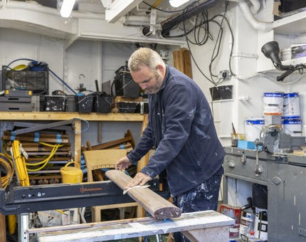 A member of the Maintenance team sanding a handrail.
