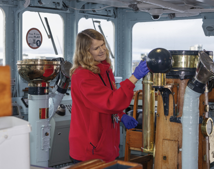 A Housekeeper polishing brass in the Bridge. 