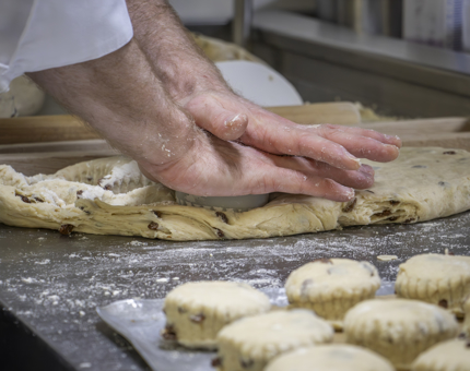 A close-up pf a chef making fruit scones. 