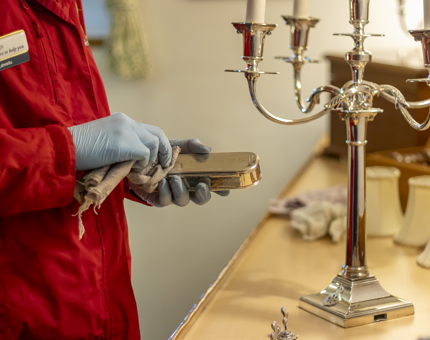 A member of the Housekeeping team is polishing silver.