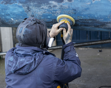A man from the Maintenance team is sanding the Admiral's Fast Motor Launch. 