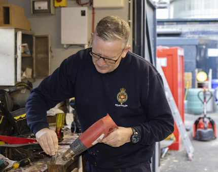 A member of Maintenance is using a heat gun to remove varnish from a step on the Officers' FML.