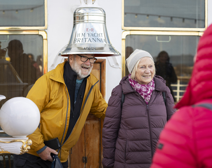 A man and a woman having their photo taken at Britannia's  bell. 